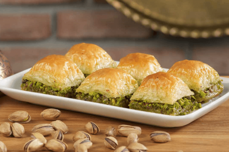 A tray of diamond-cut baklava with honey syrup and chopped walnuts