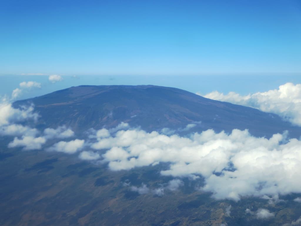 The green slopes of Mount Karthala volcano rising above the clouds on Grande Comore