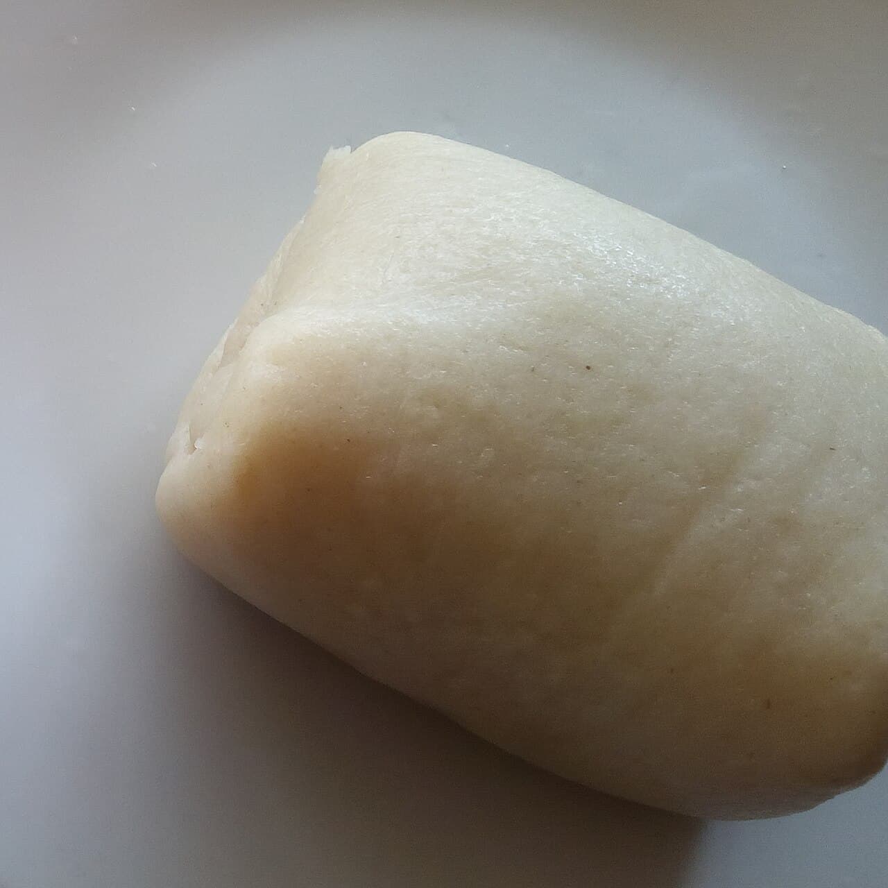 A round mound of soft white fufu served alongside a rich green vegetable stew
