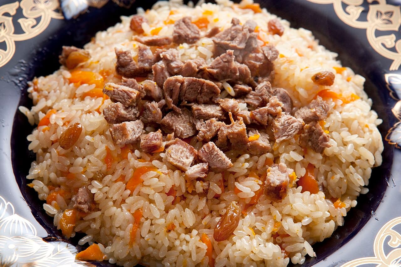 A large platter of kabuli pulao rice topped with golden carrot strips and dark raisins