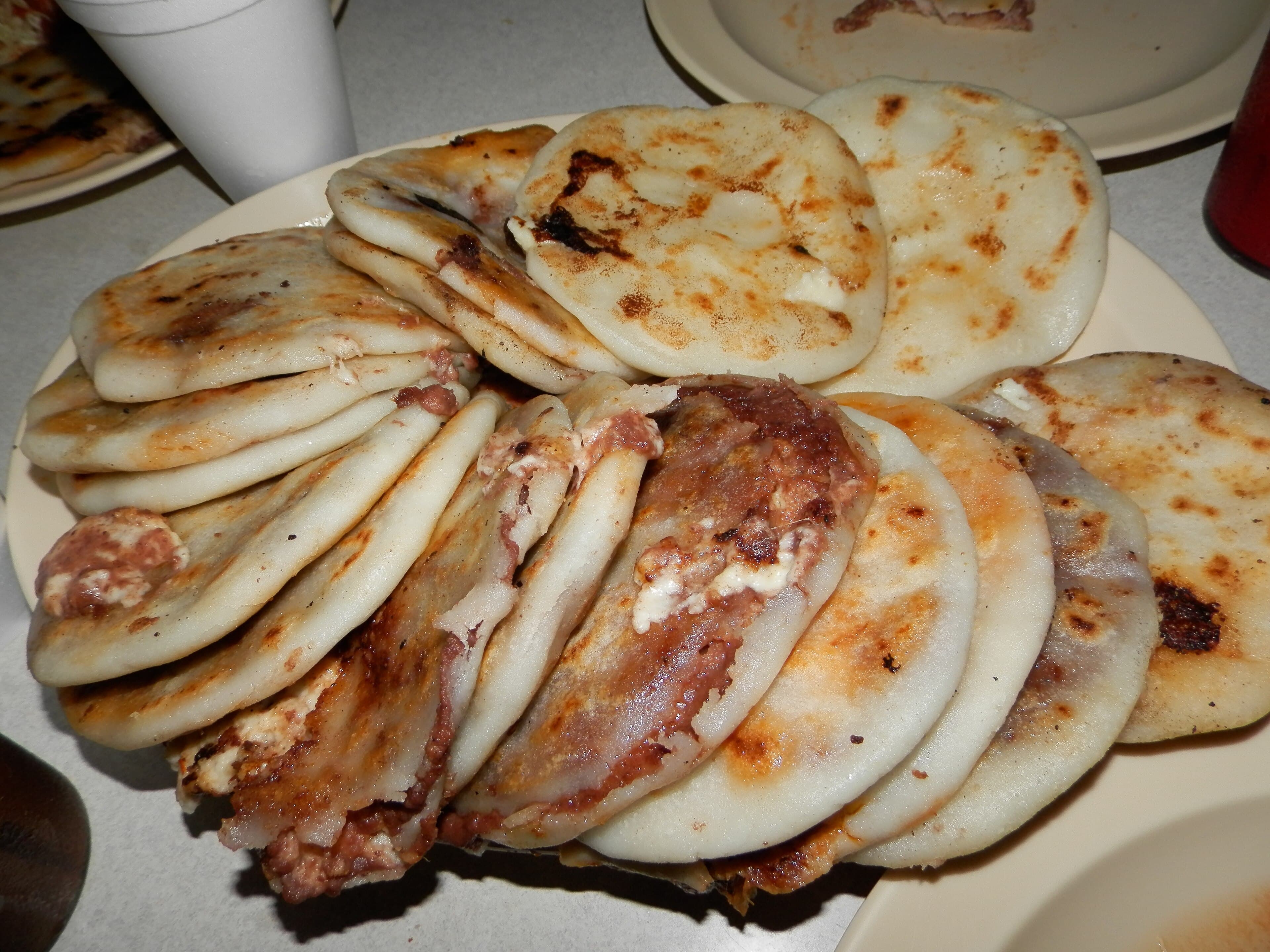 Freshly cooked pupusas on a griddle, golden-brown and steaming