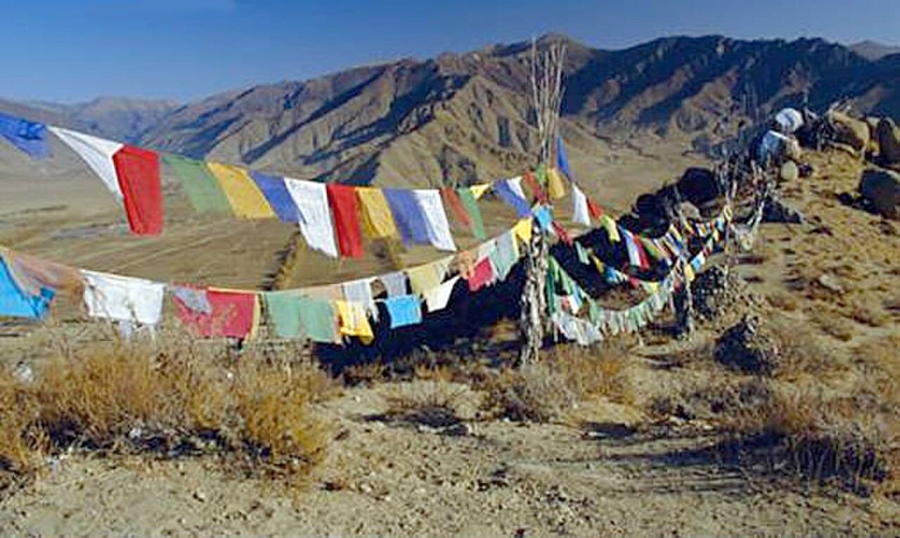 Strings of colourful prayer flags fluttering against snow-capped mountains