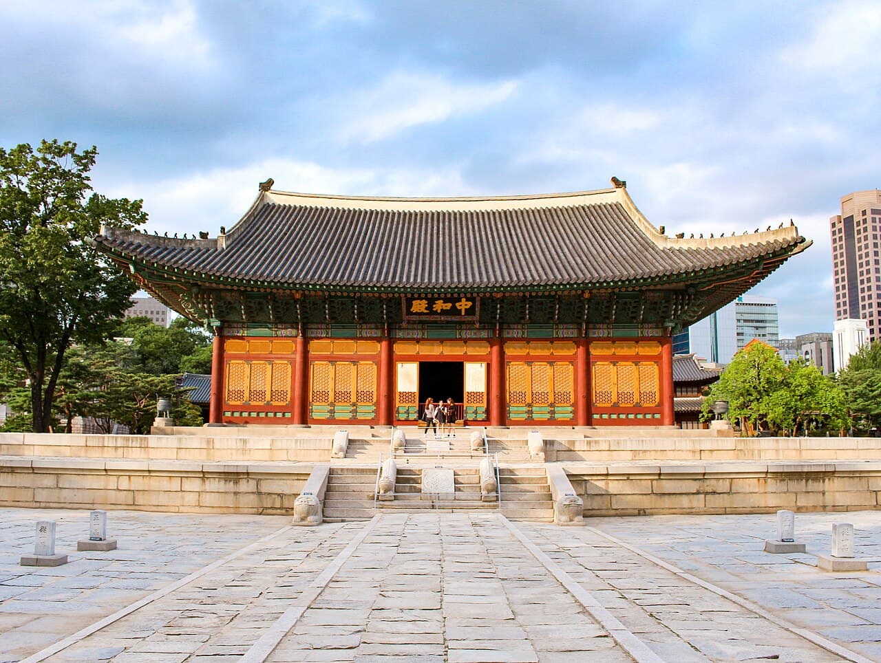 A traditional Korean palace hall with bright red columns and a curved tiled roof